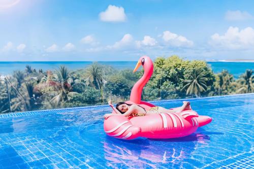 a woman riding on a pink flamingo in a swimming pool at Quinter Central Nha Trang in Nha Trang