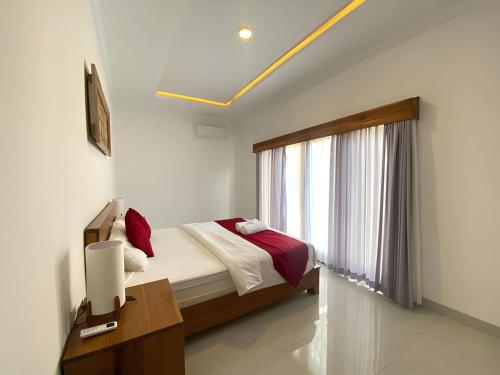 a bedroom with a bed with red pillows and a window at Villa Sinyo By Mentaripro Bali in Lovina