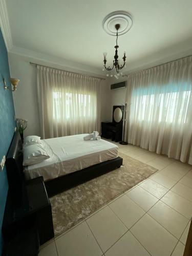 a bedroom with a large bed and a chandelier at Villa Safaa Dar Bouazza in Dar Mouddene