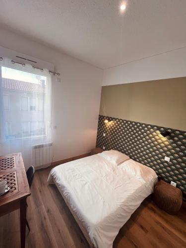 a bedroom with a large white bed with a headboard at Chambre à soulac in Soulac-sur-Mer