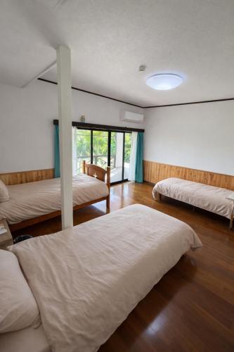 a bedroom with two beds and a large window at Lagoon藍yoron 一棟貸し in Yoron