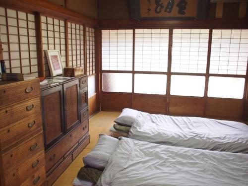 a bedroom with two beds and a dresser and windows at Ichie in Tanabe