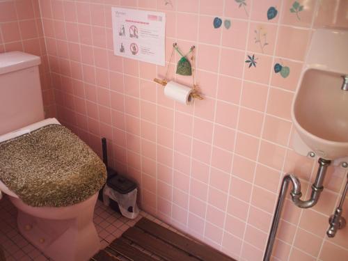 a pink bathroom with a toilet and a sink at Ichie in Tanabe