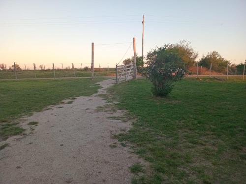 a dirt road in a field with a fence at Don Ramón in Colonia del Sacramento