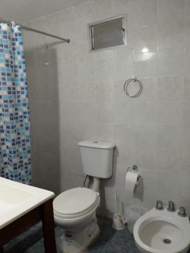 a white bathroom with a toilet and a sink at Tomás in Mar de Ajó