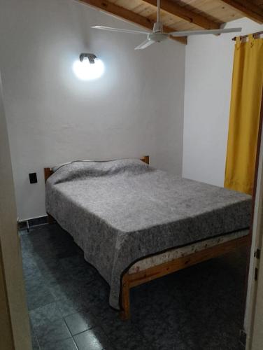 a bed in a room with a yellow curtain at Tomás in Mar de Ajó