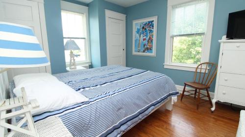 a blue bedroom with a bed and a chair at Windsor Escape in Cape May