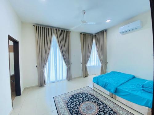 a bedroom with a bed with blue sheets and windows at SM Guest House in Changlun