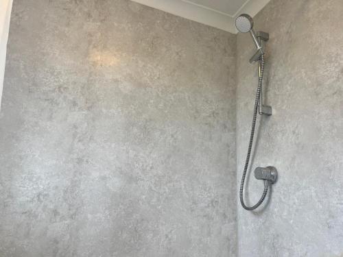 a shower with a shower head on a wall at Double Room with Garden View at Love & Peace Petts Wood in Orpington