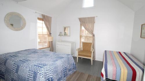 a bedroom with a bed and a chair and windows at The Elmira Escape in Cape May