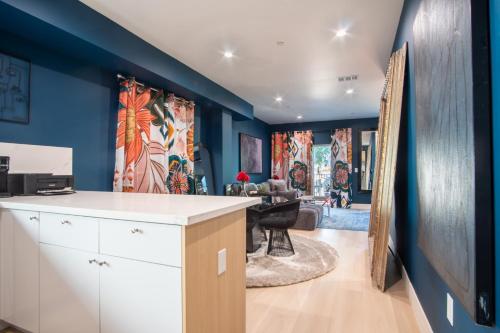 a kitchen with blue walls and a living room at Emerald Elephas at Case Collective in North Hollywood