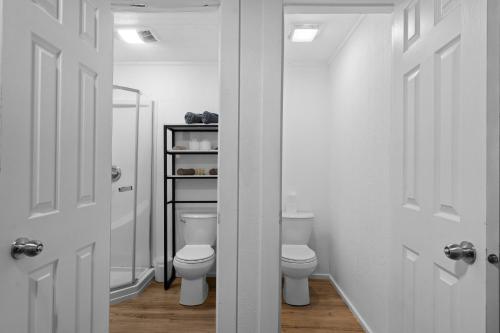 a white bathroom with two toilets and a mirror at Campfire Hollow in Eagle Rock