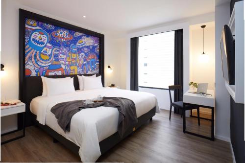 a bedroom with a large bed with a painting on the wall at de Braga, ARTOTEL Curated in Bandung
