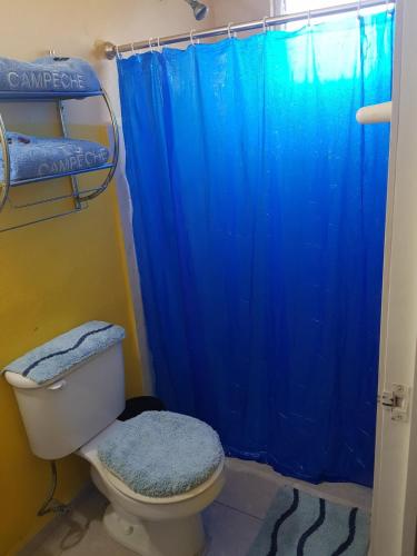a bathroom with a toilet with a blue shower curtain at Small room with bunk bed, bathroom, AC and WiFi in Ing. Alberto Acuña Ongay International Airport