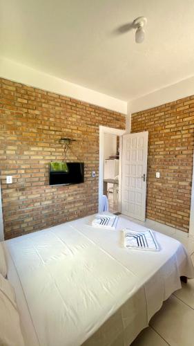 a large white bed in a bedroom with a brick wall at Chalés Santo Antônio em Flecheiras in Flecheiras