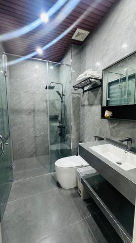 a bathroom with a shower and a toilet and a sink at Sunrise Apartments in Xóm Niêm