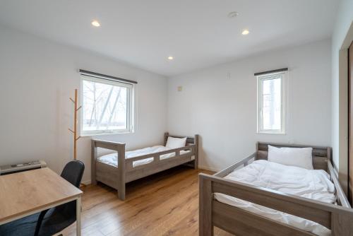 a bedroom with two beds and a desk and a table at Soga House in Niseko