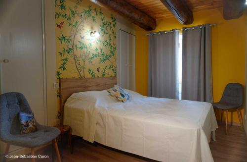 a bedroom with a white bed and two chairs at Gîte la margeride 4 personnes in Julianges