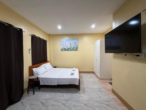 a bedroom with a bed and a flat screen tv at Boboy's Guest House in Daro