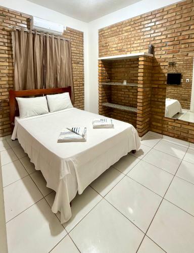 a bedroom with a large bed and a brick wall at Chalés Santo Antônio em Flecheiras in Flecheiras