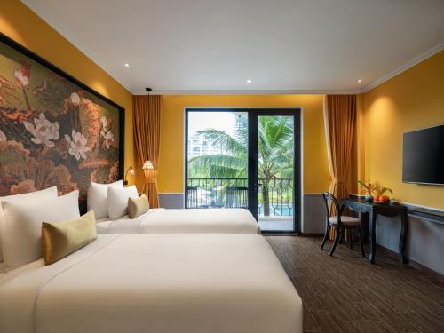 a hotel room with two beds and a television at Sen Village Hoi An in Hoi An