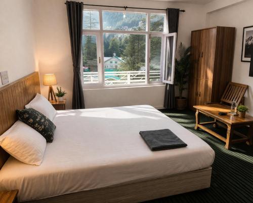 a bedroom with a large bed and a window at Apple Garden Aleo in Manāli