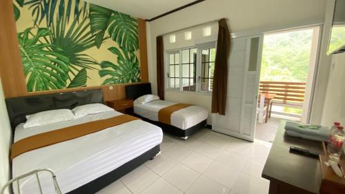 a bedroom with two beds and a desk and a balcony at Kahyuna Hotel Bromo in Sukapura