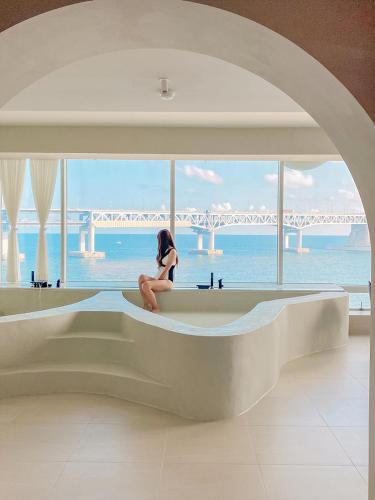 a woman sitting in a bath tub looking out at the ocean at Meomulda Subyeon in Busan