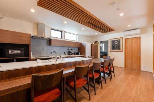 a kitchen with a bar with a sink and some chairs at Takayama Showa no yado-A Modern Japanese-style villa with garden, excellent location in Takayama