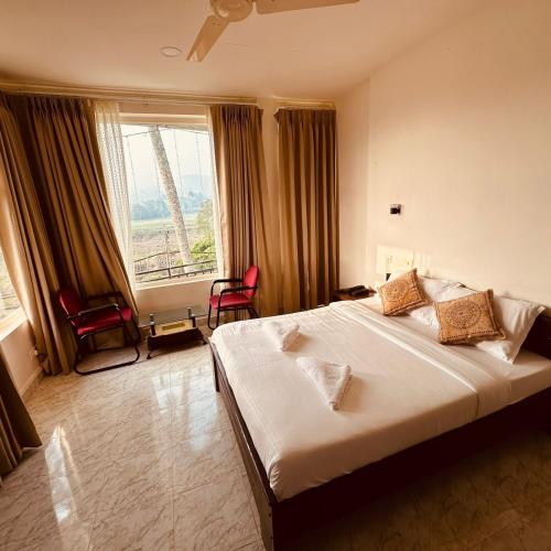a bedroom with a large bed and a large window at The Thekkady Haritham Residency in Thekkady