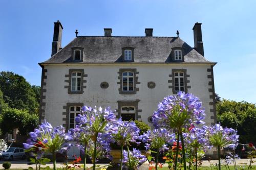 an old house with purple flowers in front of it at Chambres d'Hôtes Launay Guibert in Miniac-Morvan