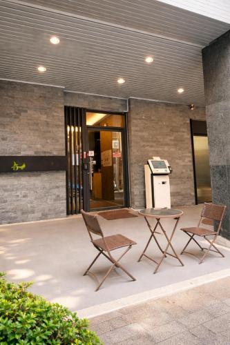 two chairs and a table in front of a building at 逢甲25行館Fengjia 25 Hotel in Taichung