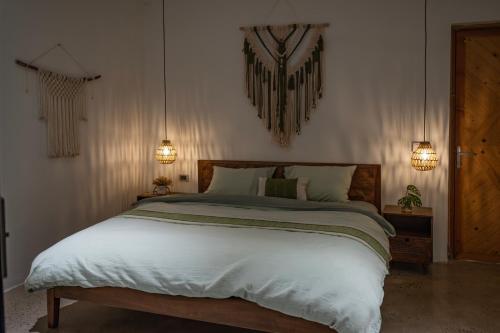 a bedroom with a large bed with two lights on the wall at KuTÓN ECOCAMP in Lương Sơn