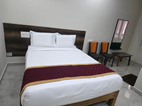 a large bed in a room with two chairs at RK Residency in Tirupati