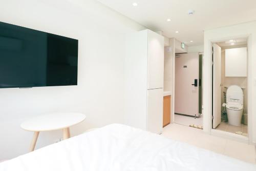 a bathroom with a toilet and a tv on a wall at 더 신촌스테이 레지던스 in Seoul