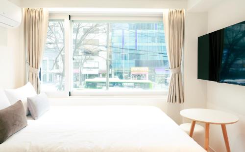 a bedroom with a white bed and a window at 더 신촌스테이 레지던스 in Seoul