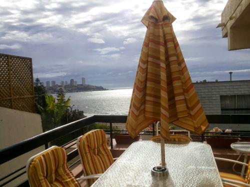 a table with an umbrella on top of a balcony at Apartamento en Edificio Las Arenas in Concón