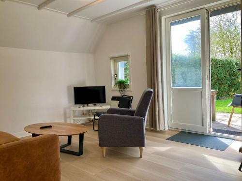a living room with a couch and a chair and a tv at Olivia 6pers House with a private garden close to the National Park Lauwersmeer in Anjum