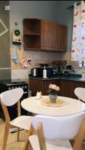 a kitchen with a white table and chairs and a kitchen with a stove at Malaika homes in Kampala