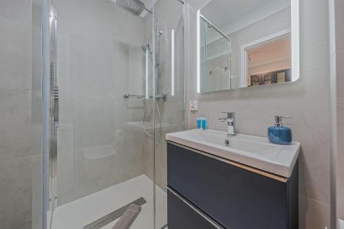 a white bathroom with a sink and a shower at Azure Mostek Oldtown in Gdańsk