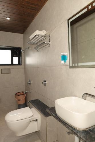 a bathroom with a white sink and a toilet at Anusha Hotel in Nashik