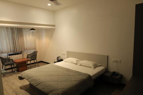 a bedroom with a bed and a desk and a chair at Anusha Hotel in Nashik