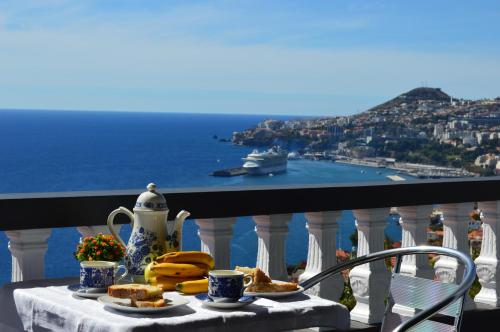 a table with food on a balcony with a view of the ocean at Charming Apartments in Funchal - São Gonçalo in Funchal