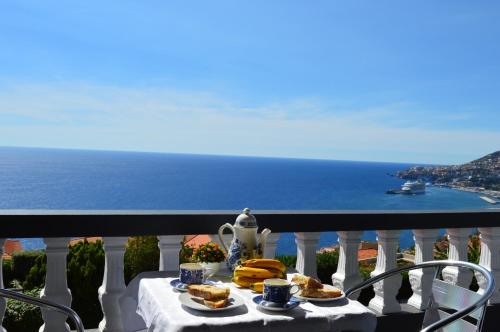 a table with food on a balcony overlooking the ocean at Charming Apartments in Funchal - São Gonçalo in Funchal