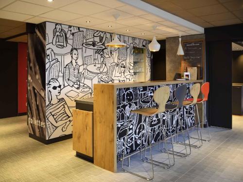 a bar with stools and a wall covered in graffiti at ibis Saint-Denis Stade Ouest in Saint-Denis