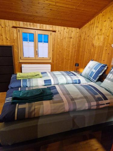 a large bed in a room with wooden walls at Chalet Marguerite in Flums