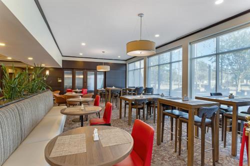a restaurant with tables and chairs and windows at Hilton Garden Inn Houston NW America Plaza in Houston