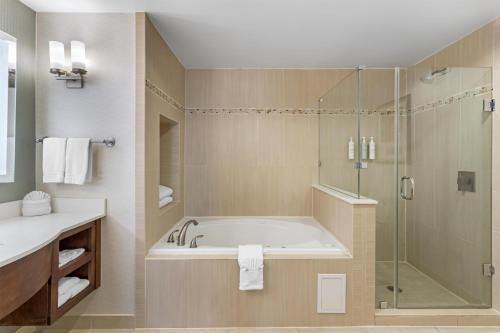 a bathroom with a tub and a glass shower at Hilton Garden Inn Houston NW America Plaza in Houston