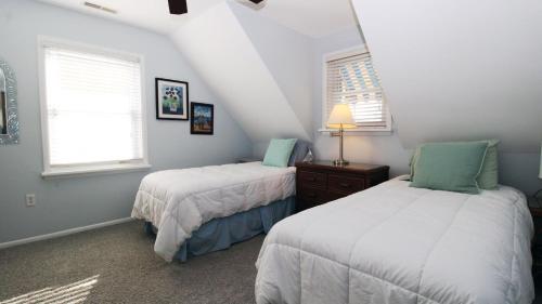 two beds in a room with two windows at The Roost Ii On Leaming in West Cape May