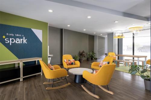 a waiting room with yellow chairs and a table and a sign at Spark by Hilton Virginia Beach Oceanfront in Virginia Beach